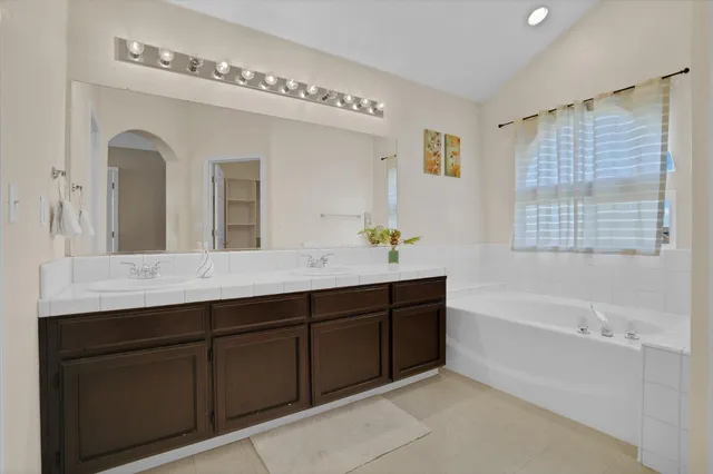 a spacious bathroom with a tub double sink and mirror