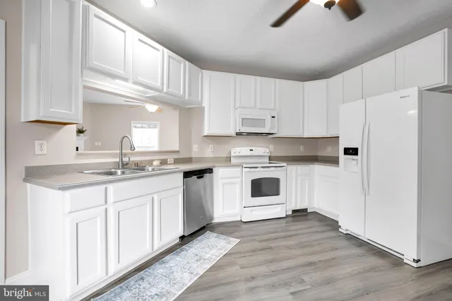 a kitchen with granite countertop white cabinets and white appliances