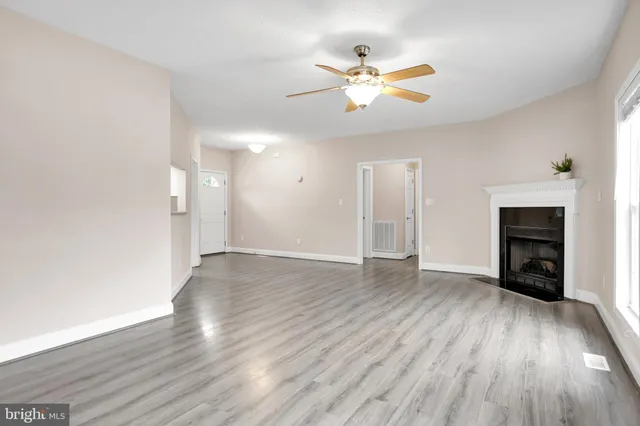 an empty room with wooden floor chandelier fan and windows