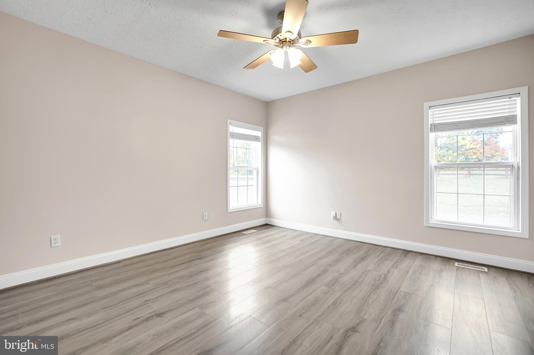 10717 Mt Sharon Road Orange, VA 22960 - Photo 19 of 35 an empty room with wooden floor chandelier fan and windows