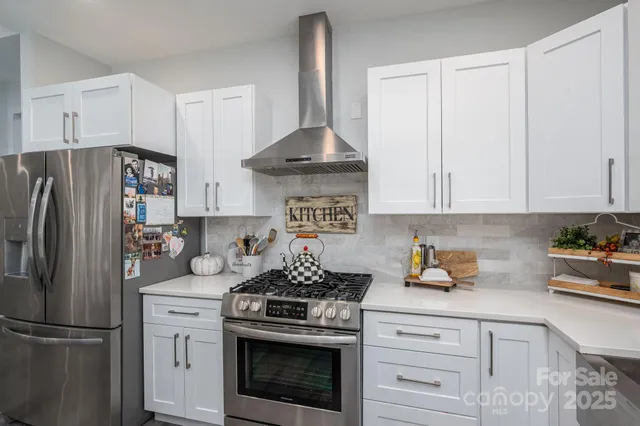 a kitchen with stainless steel appliances granite countertop a refrigerator a stove a sink and white cabinets
