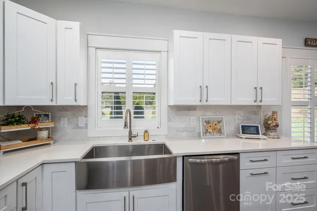 a kitchen with stainless steel appliances white cabinets and a window