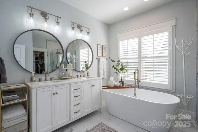 a spacious bathroom with a granite countertop sink a mirror a bathtub and next to a window