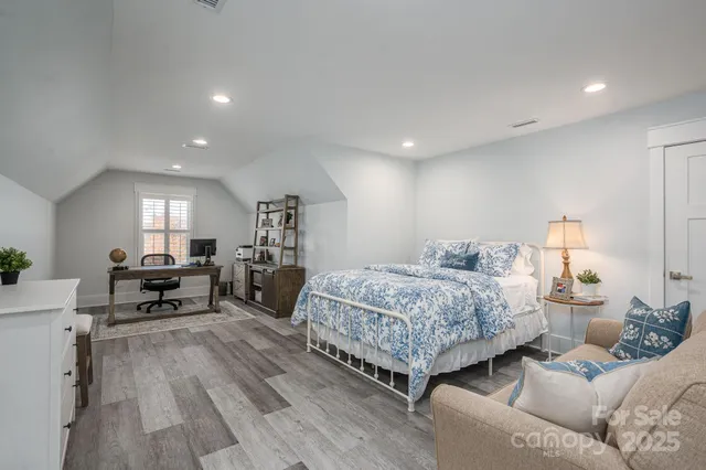 a bedroom with a bed a table and chairs with wooden floor