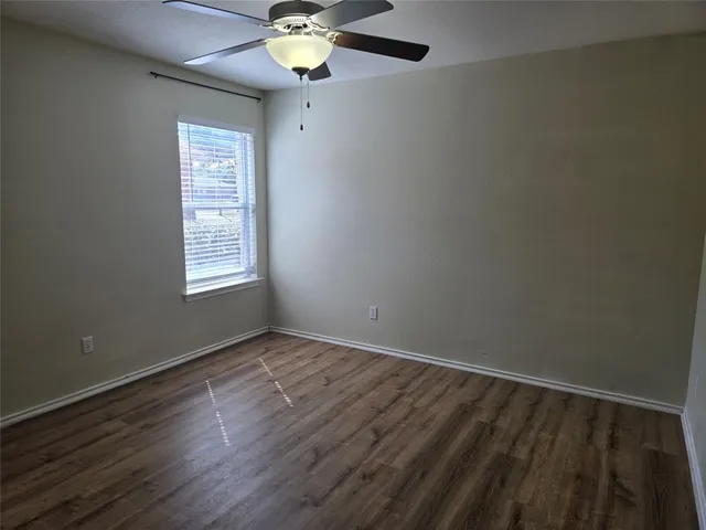 an empty room with wooden floor chandelier fan and windows
