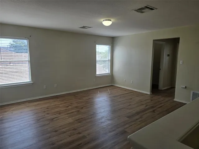 a view of an empty room with wooden floor and a window