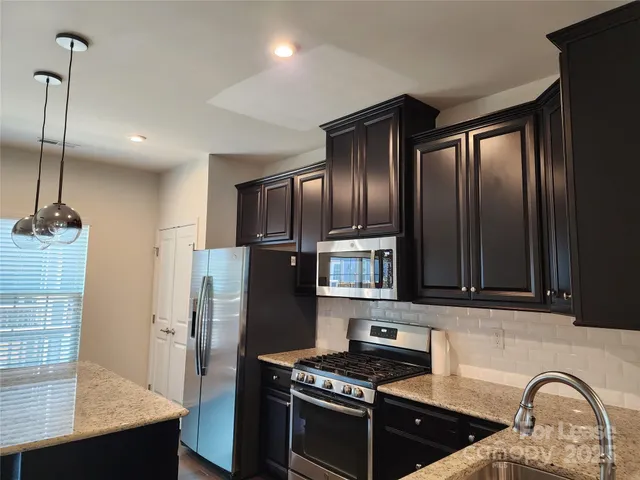 a kitchen with stainless steel appliances granite countertop a refrigerator a stove and a sink with wooden floor