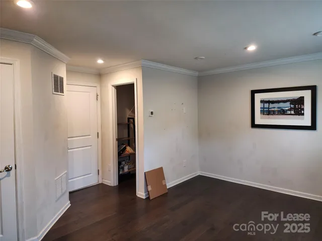 a view of an empty room with wooden floor and closet