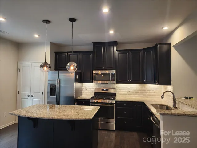 a kitchen with granite countertop a sink stove and refrigerator