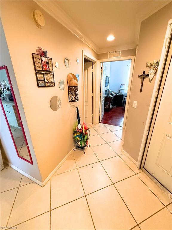 8490 Kingbird Loop, Unit 930 Estero, FL 33967 - Photo 6 of 12 Corridor featuring light tile patterned floors and crown molding