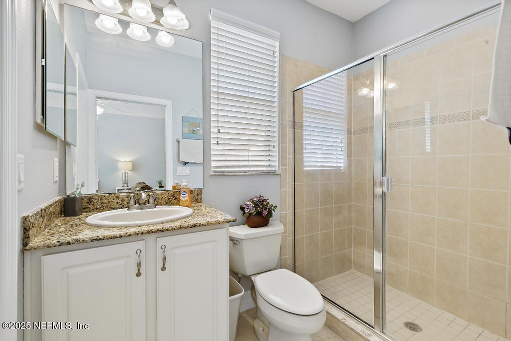 555 Hedgewood Drive St. Augustine, FL 32092 - Photo 46 of 70 a bathroom with a granite countertop sink a toilet a mirror and shower