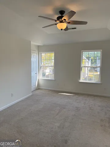 an empty room with windows and ceiling fan