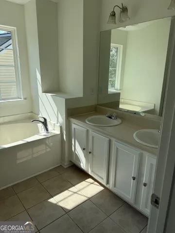 a bathroom with a sink vanity granite tub and a mirror