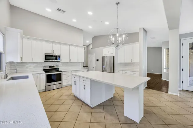 a large kitchen with granite countertop a stove top oven a sink a counter top space and cabinets