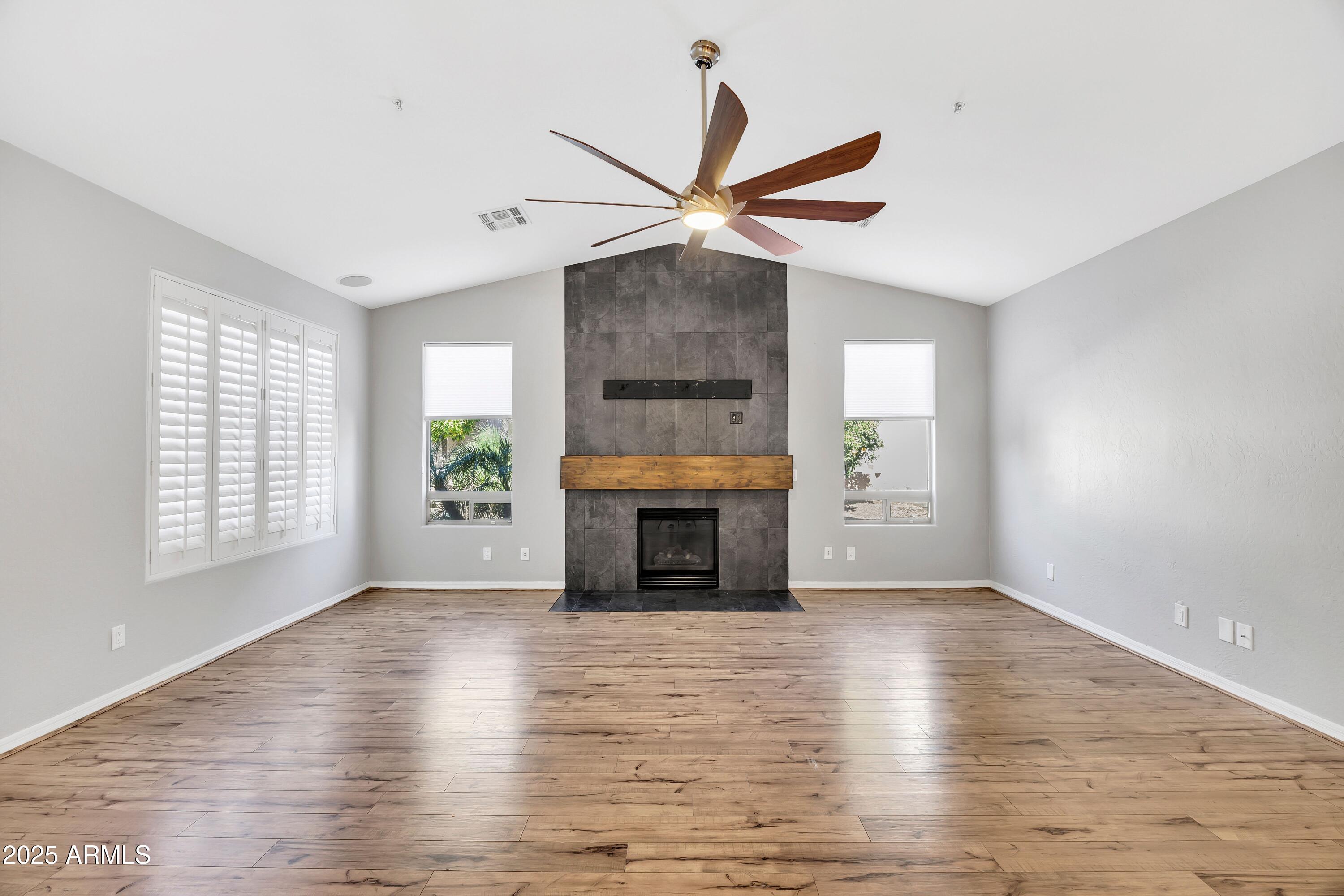 7446 East Glenn Moore Road Scottsdale, AZ 85255 - Photo 6 of 18 an empty room with windows fireplace and a ceiling fan