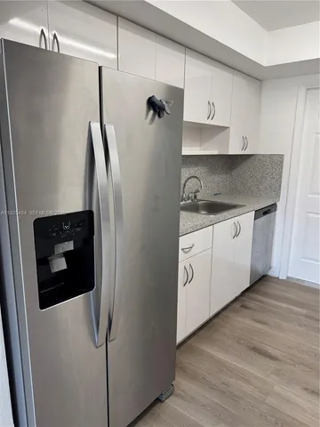 a kitchen with a refrigerator sink and cabinets