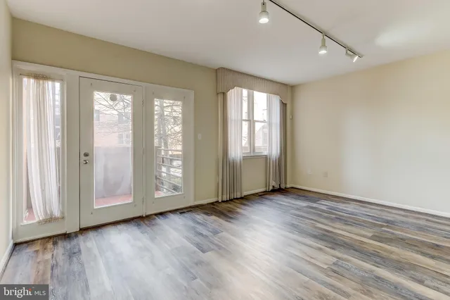 a view of an empty room with wooden floor and a window