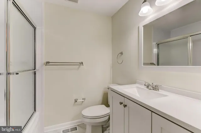 a bathroom with a granite countertop sink toilet and a mirror