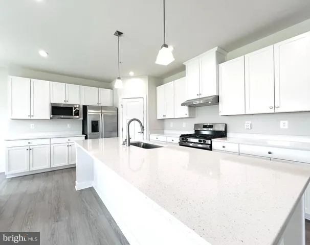 a large kitchen with stainless steel appliances granite countertop a stove a sink a center island and cabinets