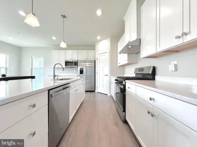 a large white kitchen with lots of counter space a sink and appliances