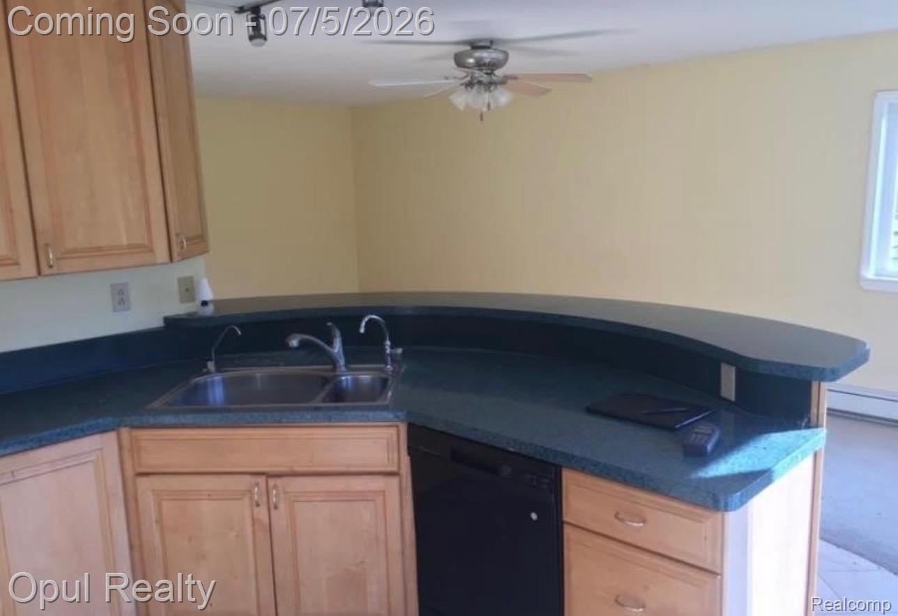 7503 Reading Road East Pittsford, MI 49271 - Photo 5 of 24 Kitchen featuring a curved breakfast bar with a built-in double basin stainless steel sink, light wood-finish cabinetry, and a black dishwasher