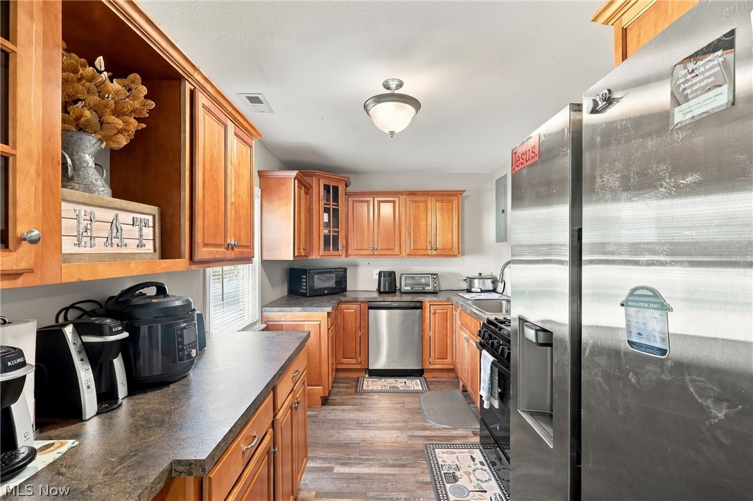 1875 Perth Road Madison, OH 44057 - Photo 5 of 48 Kitchen featuring wood-finish cabinetry, dark countertops, stainless steel appliances, and wood-finish flooring