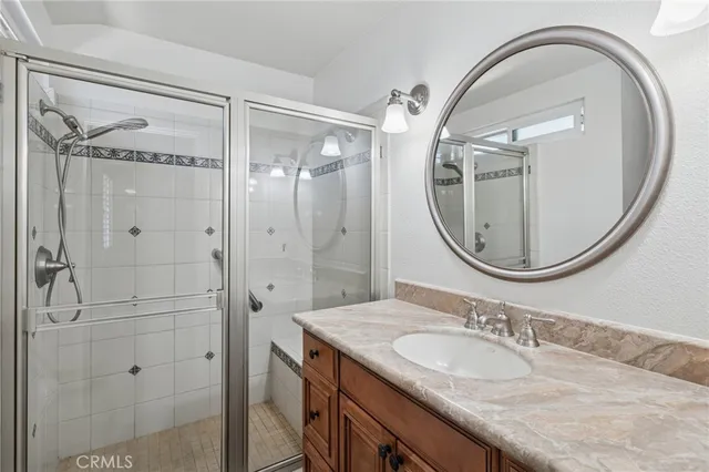 a bathroom with a granite countertop sink a mirror a vanity and a shower