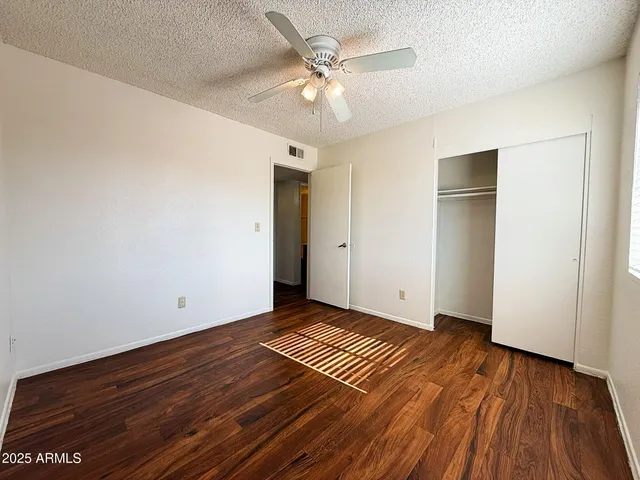 an empty room with wooden floor and a ceiling fan
