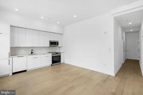 a large white kitchen with granite countertop white cabinets and stainless steel appliances