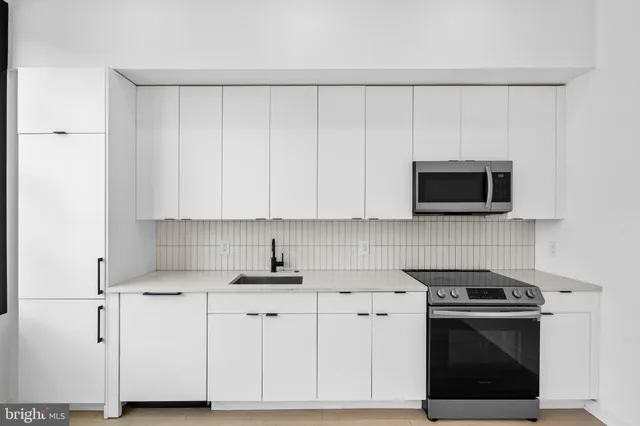 a kitchen with white cabinets and stainless steel appliances