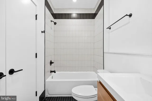 a bathroom with a bathtub shower sink vanity and toilet