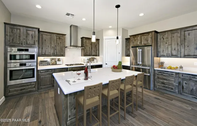 a kitchen with stainless steel appliances kitchen island granite countertop a refrigerator a stove a microwave oven a sink with island and chairs