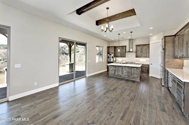 a large kitchen with stainless steel appliances granite countertop a large center island a sink dishwasher and a stove with wooden floor