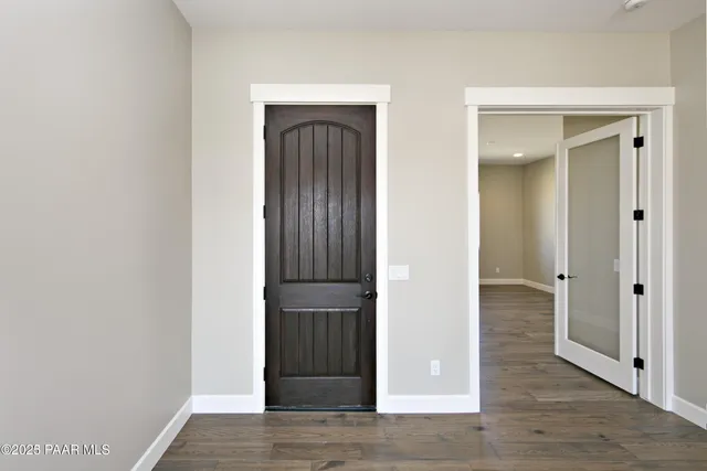 an empty room with wooden floor closet and windows