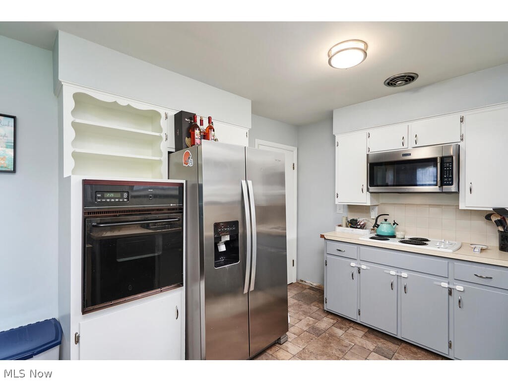 2953 Sweitzer Road Uniontown, OH 44685 - Photo 7 of 14 Kitchen featuring appliances with stainless steel finishes, backsplash, and tile flooring