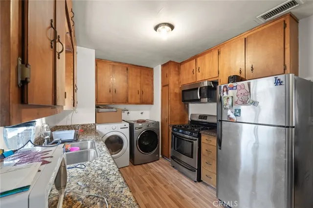 a kitchen with stainless steel appliances granite countertop a refrigerator a stove and a sink with wooden floor