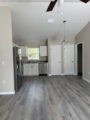 an empty room with wooden floor and a kitchen