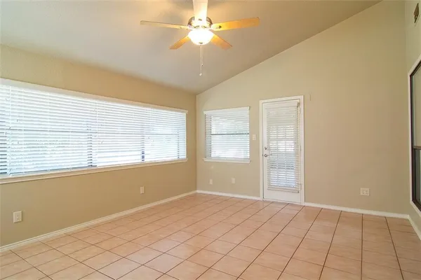 a view of an empty room with window and chandelier fan