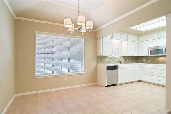 a large white kitchen with granite countertop a stove a sink dishwasher and white cabinets with wooden floor