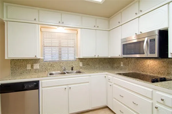 a kitchen with stainless steel appliances granite countertop white cabinets granite counter tops and a window
