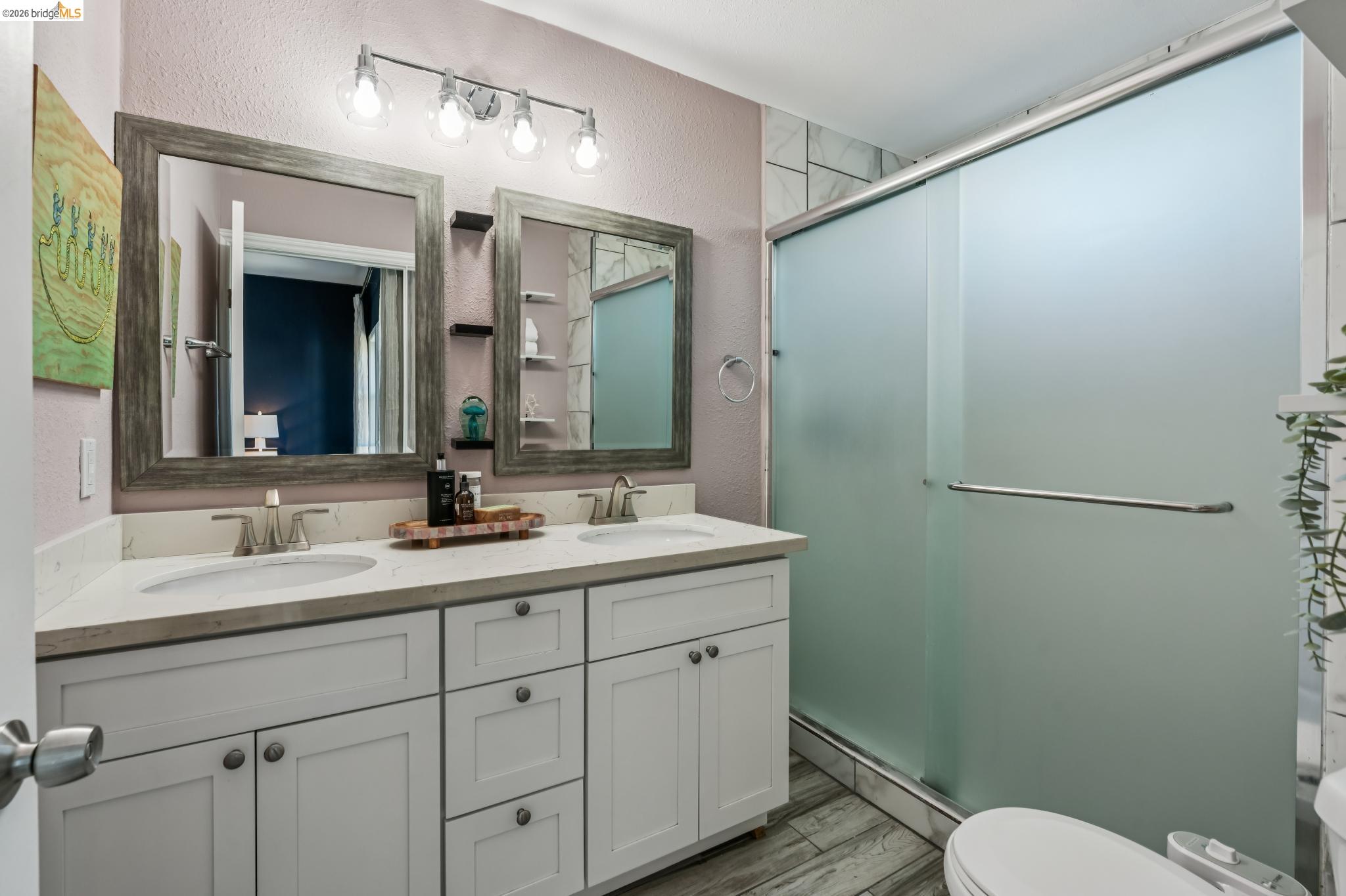 2010 Filbert Street Oakland, CA 94607 - Photo 17 of 50 Full bathroom featuring a textured wall, double vanity, a shower stall, and dark wood-type flooring