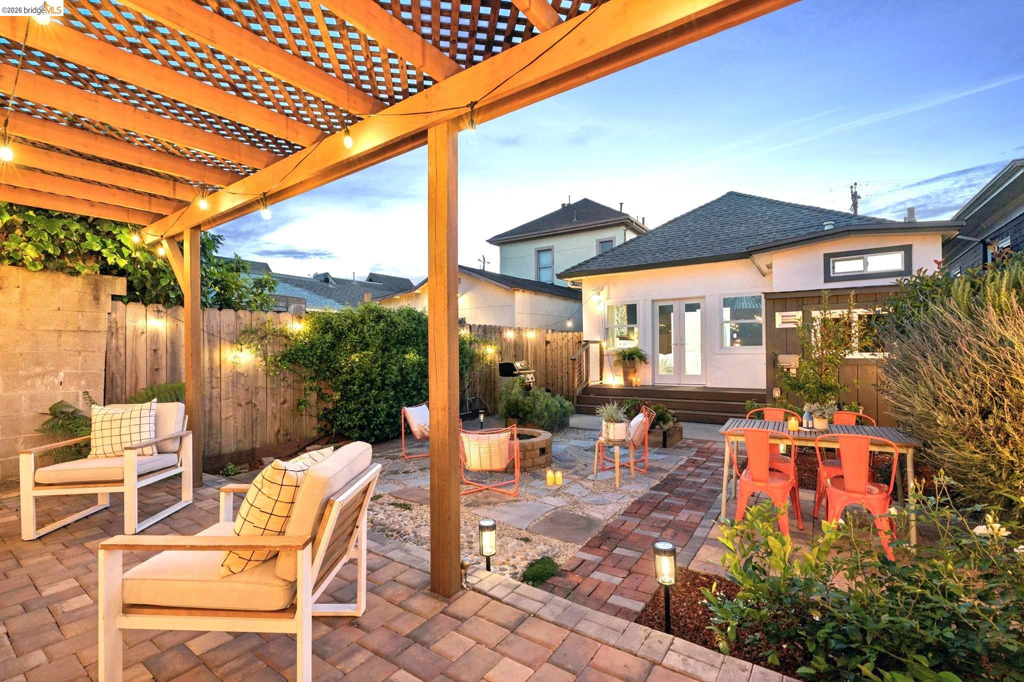 2010 Filbert Street Oakland, CA 94607 - Photo 45 of 50 Patio terrace at dusk featuring french doors, a fenced backyard, a patio area, an outdoor fire pit, and outdoor dining space