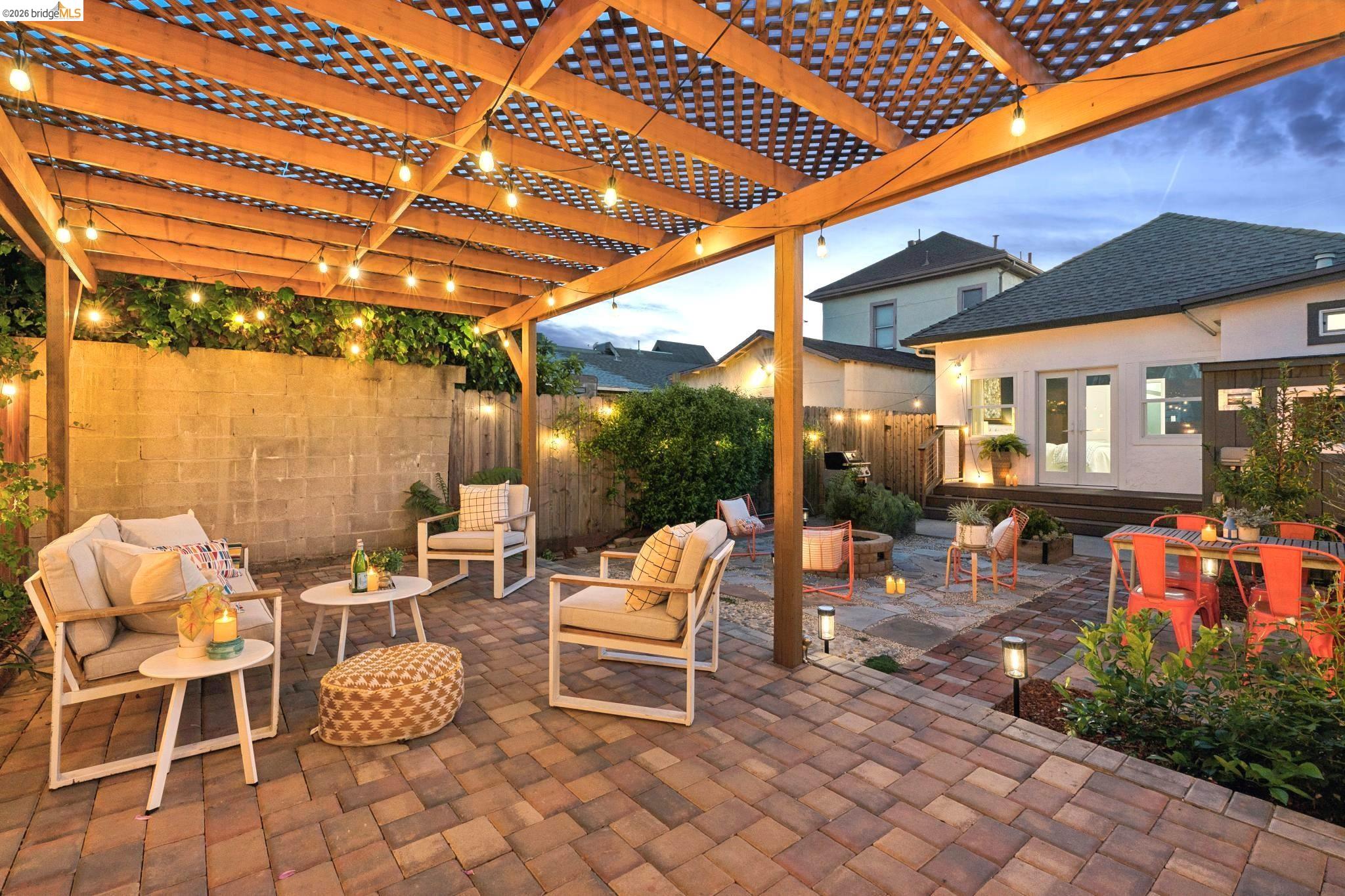 2010 Filbert Street Oakland, CA 94607 - Photo 46 of 50 Patio terrace at dusk featuring french doors, a patio, a fenced backyard, an outdoor living space, and a pergola