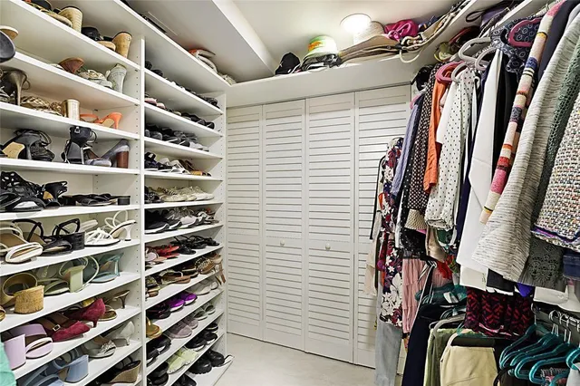 a view of walk in closet with clothes and shoes