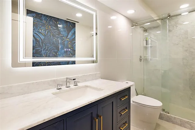 a bathroom with a sink a toilet a mirror and a shower