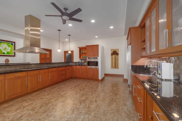 a large kitchen with a large counter top a sink stainless steel appliances and cabinets