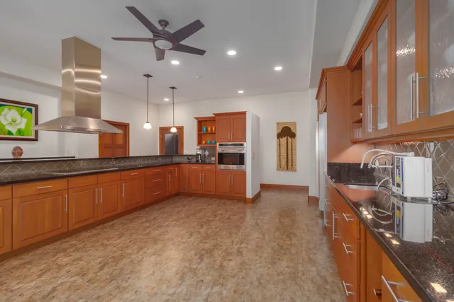 a large kitchen with a large counter top a sink stainless steel appliances and cabinets