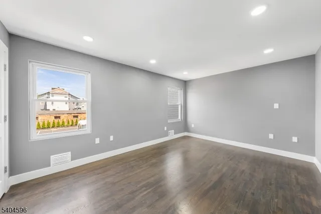 an empty room with windows and wooden floor