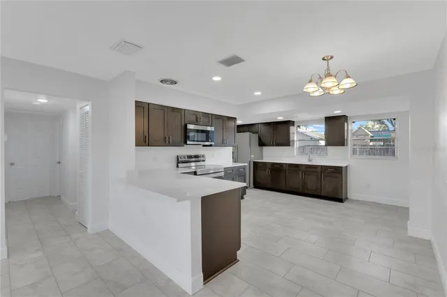 a large white kitchen with a white countertops a fireplace and a flat screen tv