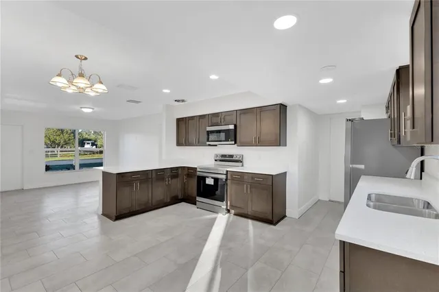 a large living room with stainless steel appliances granite countertop couches a flat screen tv and kitchen view